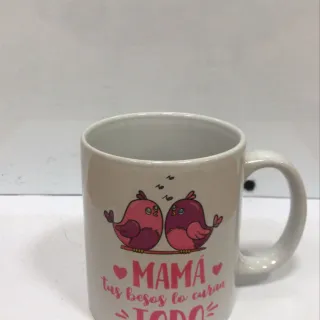 Taza blanca con mensaje “Mamá, tus besos lo curan todo” en letras rosas y detalles florales delicados.